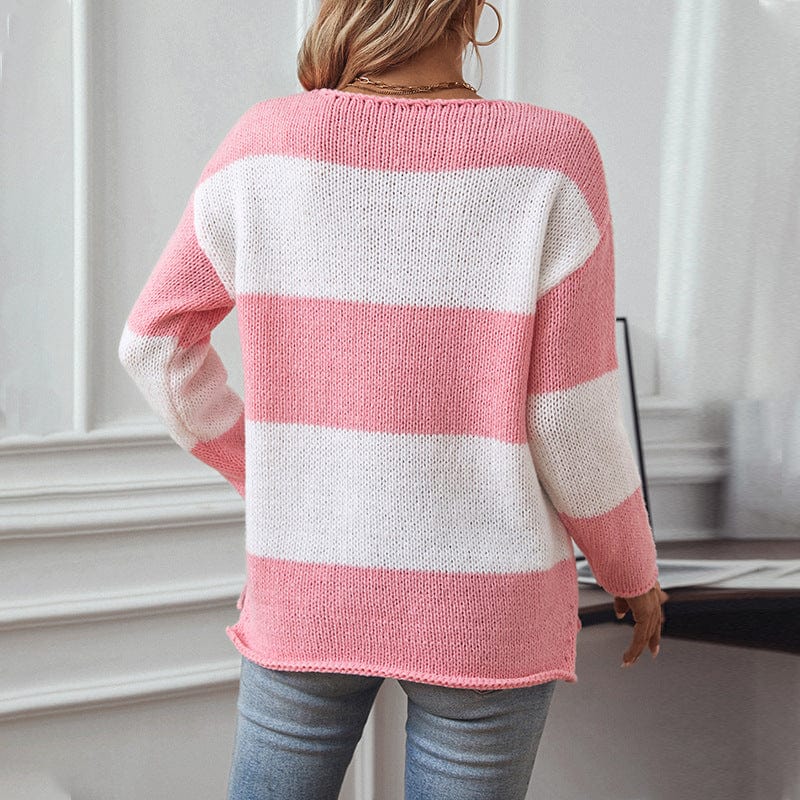 Person in pink and white v neck striped sweater with blue jeans against white wall